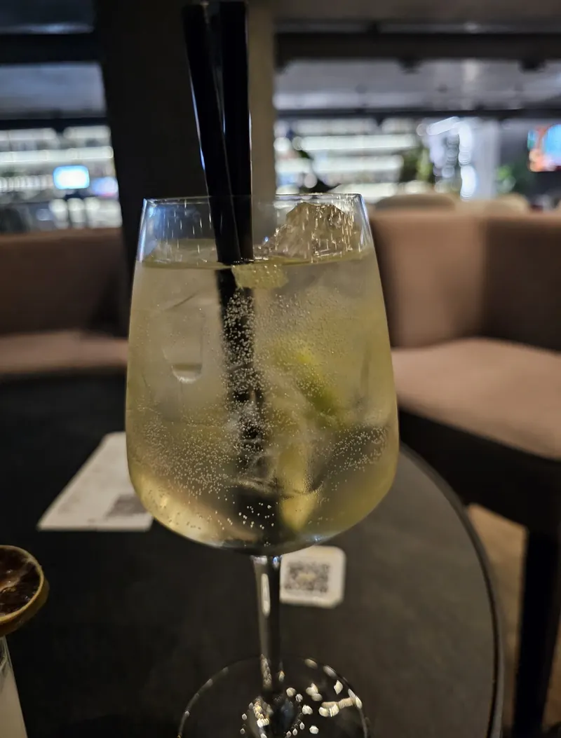A tall glass of a sparkling drink with lime on a lounge table
