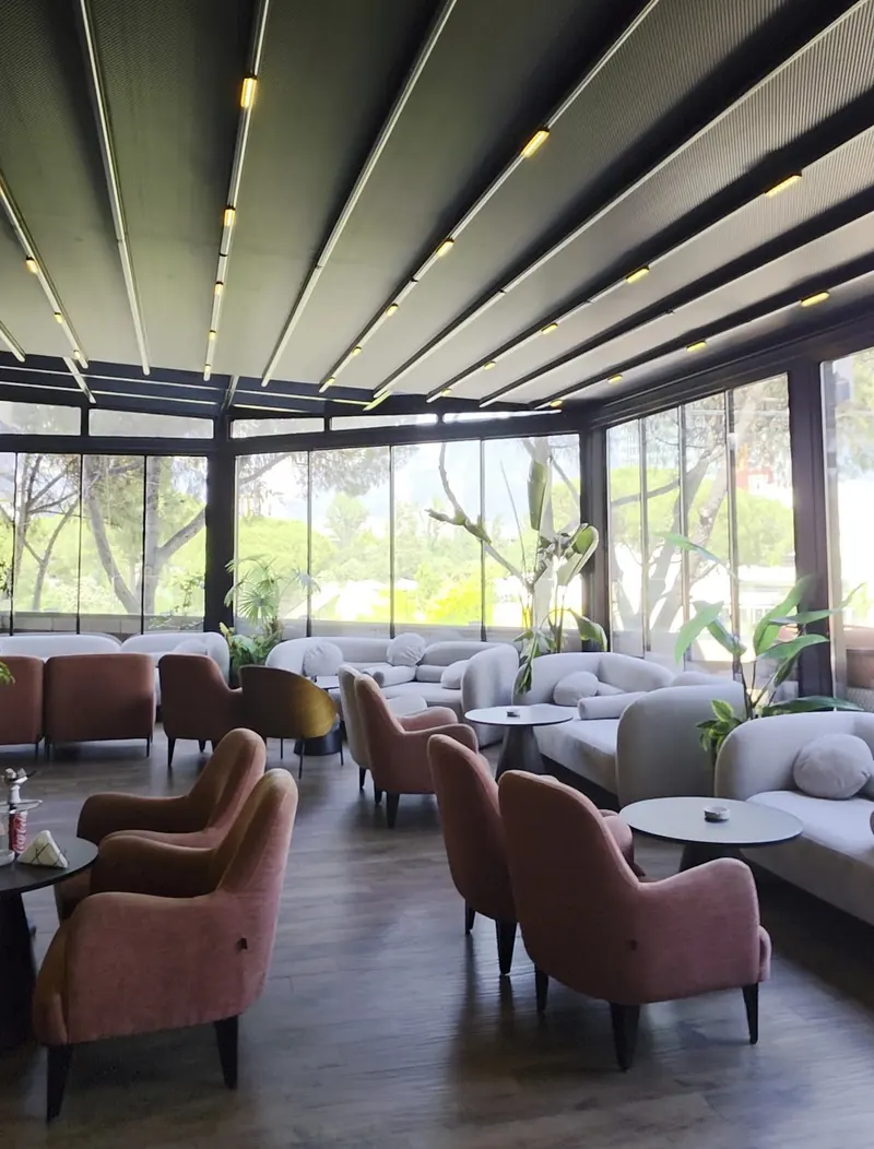The covered terrace with pink armchairs, glass walls and lines of ceiling lights