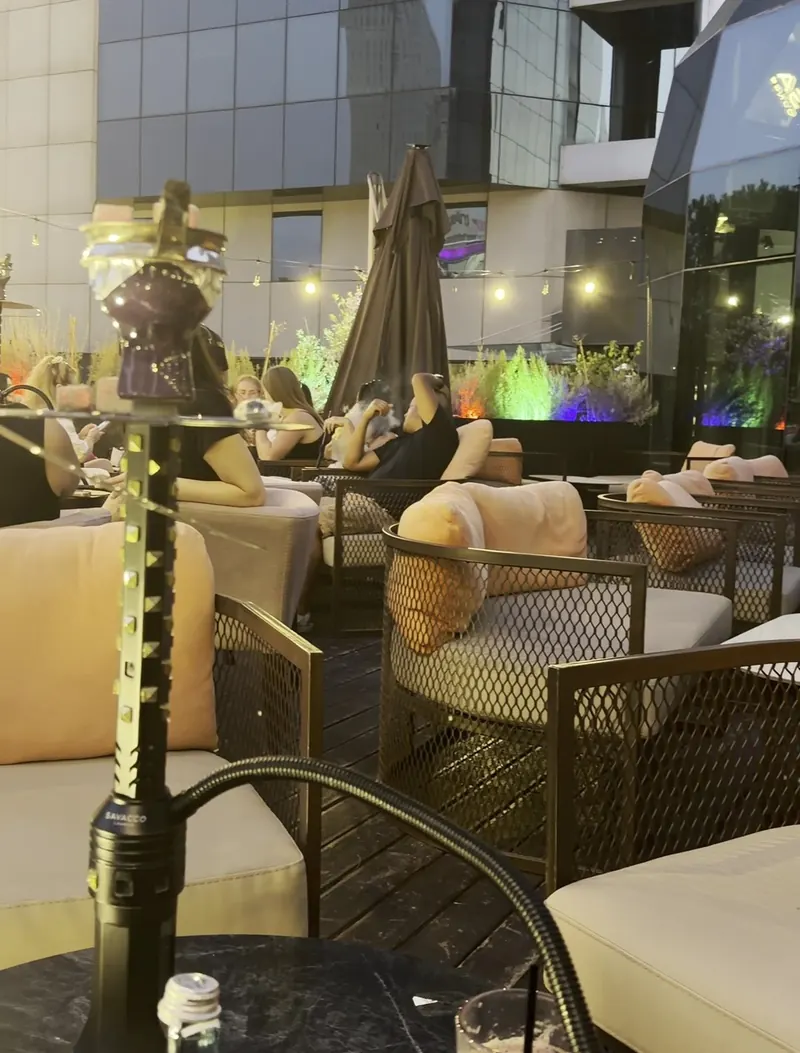 A shisha on the terrace at dusk, with string lights and the towers behind