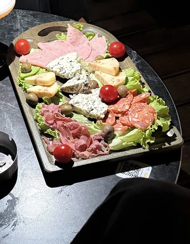 A board of cured meats and cheese with an orange cocktail