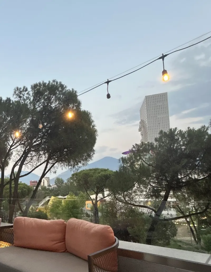 The terrace at dusk: pines, string lights, mountains in the distance and a tower on the right