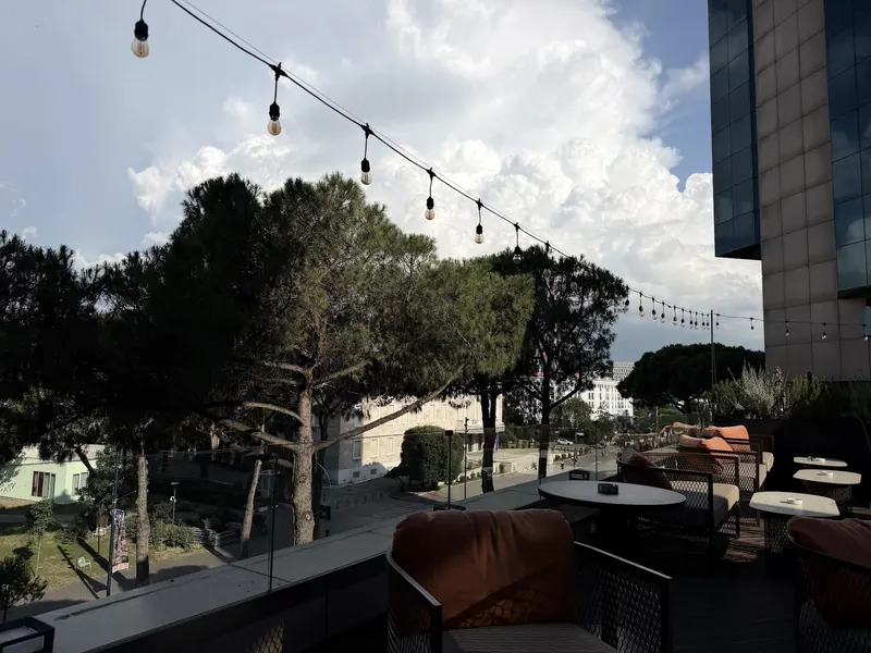 The Twiga terrace by day: string lights over the pines, the glass towers on the right